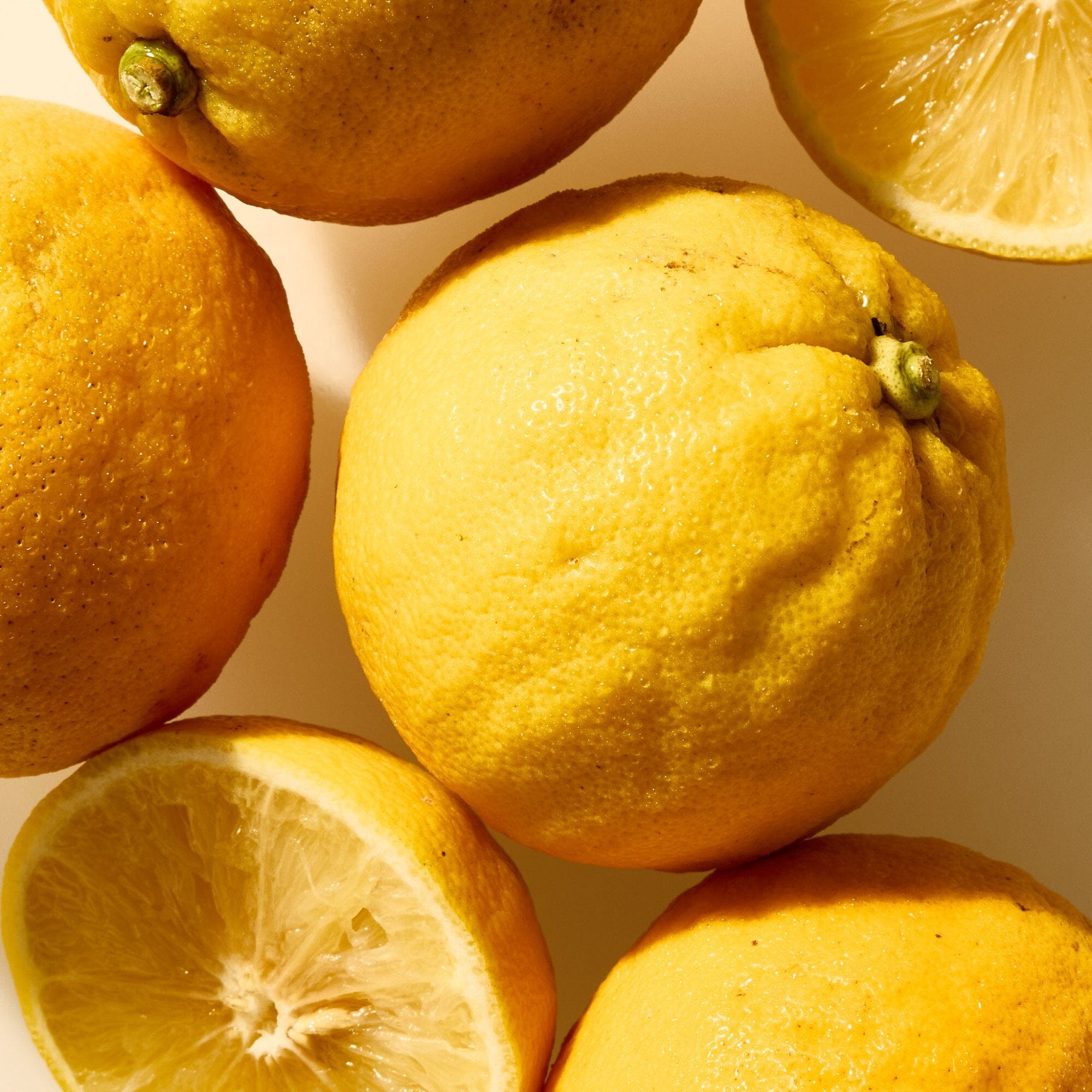 Several whole and halved lemons rest on a light surface, their vibrant appeal pairing perfectly with the aroma of Rishi Tea & Botanicals organic Earl Grey, infused with bergamot essential oil.
