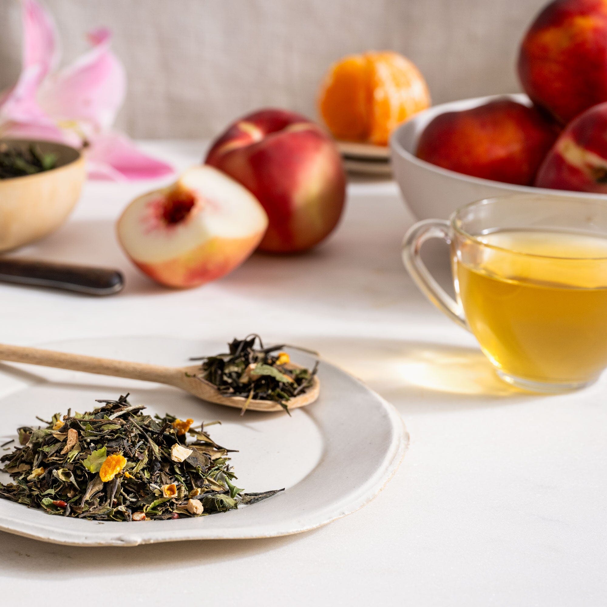 A white plate with a cup of Peach Blossom tea from Rishi Tea & Botanicals and a bowl of peaches.
