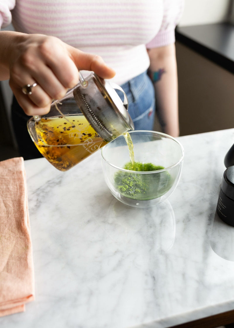 Woman pours tea over matcha powder in bowl