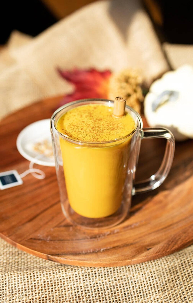 Creamy pumpkin latte in a glass mug with a cinnamon stick for garnish