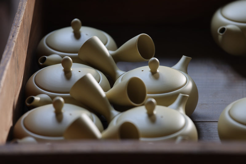 Collection of ceramic teapots in a wooden box