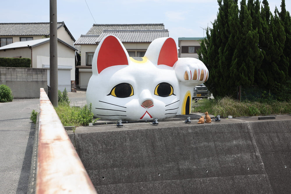 Large cat-shaped object on a concrete ledge with residential buildings in the background