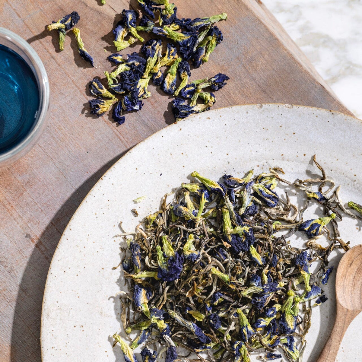 A plate of Blue Jasmine tea from Rishi Tea & Botanicals with blue flowers and a spoon next to it.