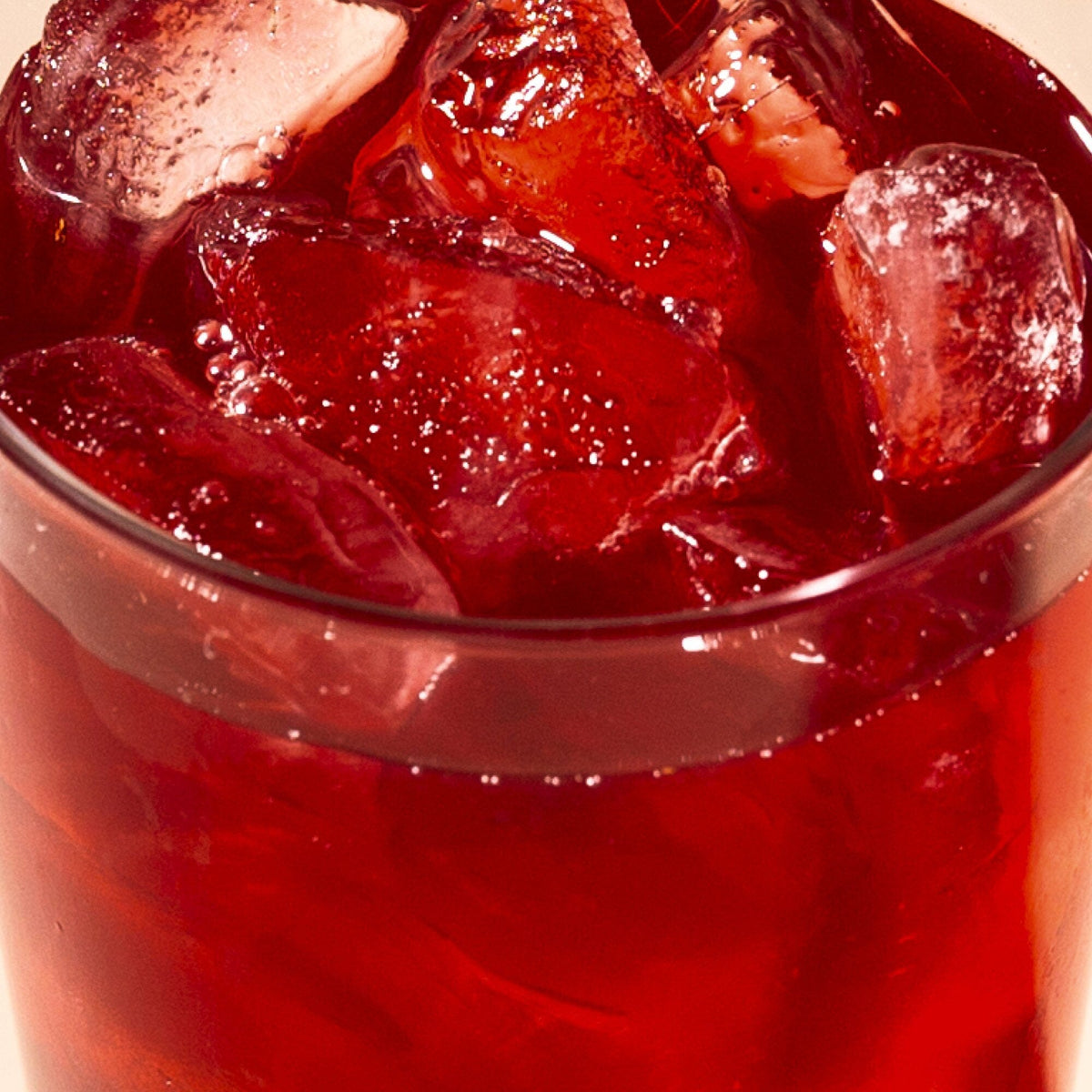 A close-up view of a glass filled with refreshing Rishi Tea & Botanicals Blueberry Hibiscus iced beverage and several ice cubes.