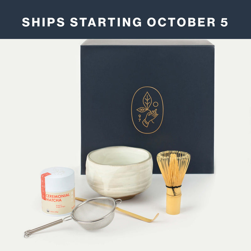 A premium Matcha Set featuring essential Matcha Tools: a tin of ceremonial matcha, a bowl, a bamboo whisk, a strainer, and a scoop, all elegantly displayed with a black box behind them. Text reads, “SHIPS STARTING OCTOBER 5.”.