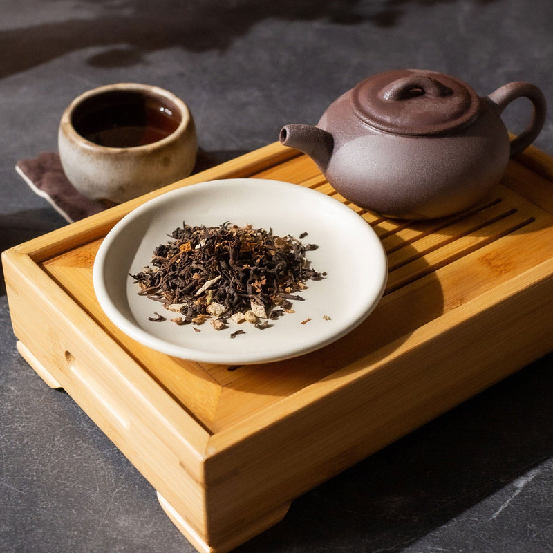 A pile of vintage Orange Blossom Pu'er from Rishi Tea & Botanicals on a white background.