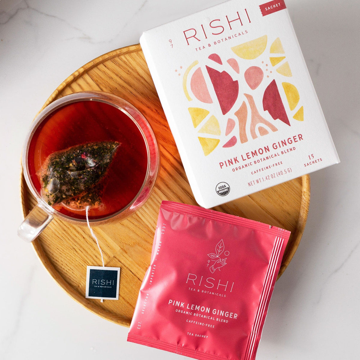 Pink Lemon Ginger tea from Rishi Tea & Botanicals on a plate next to a bag of ginger tea.