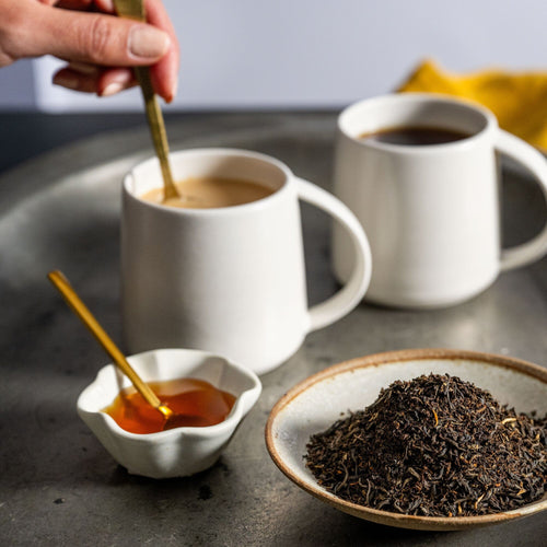 A person is pouring Rishi Tea & Botanicals English Breakfast into a cup on a tray.