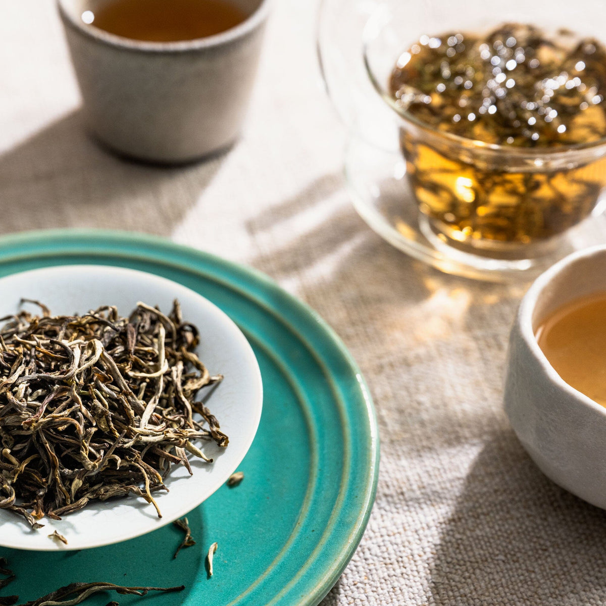 A bowl of Moonlight Jasmine tea and a cup of Moonlight Jasmine tea on a plate. (Brand: Rishi Tea & Botanicals)