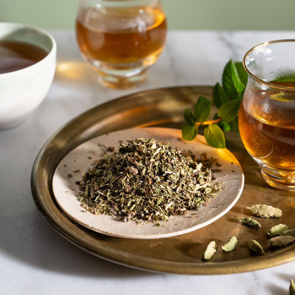 A plate with a cup of Mystic Mint tea and some herbs on it, from Rishi Tea & Botanicals.