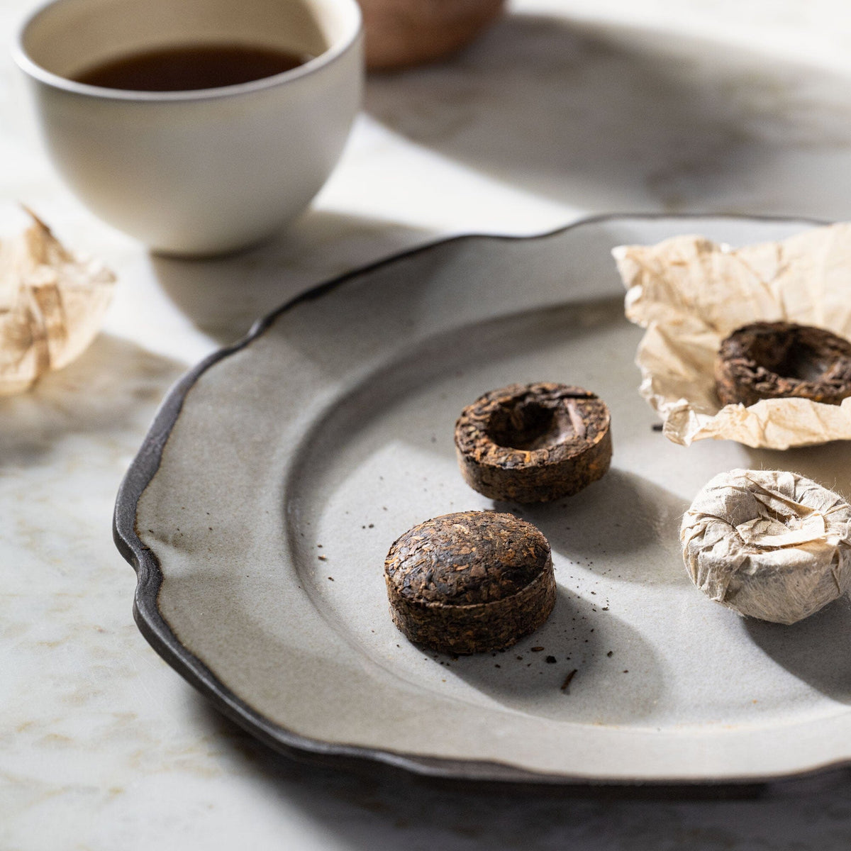 A plate with some Pu’er Tuo Cha cookies and a cup of Rishi Tea & Botanicals tea.