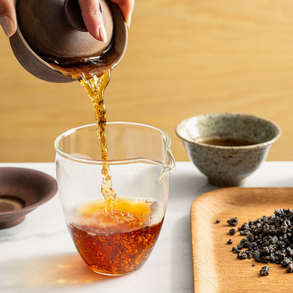 A person pouring Ruby Oolong tea from Rishi Tea & Botanicals into a cup on a table.