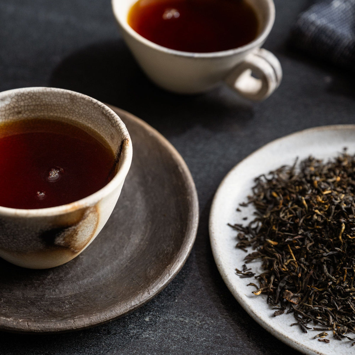 A cup of Vanilla Bean tea from Rishi Tea & Botanicals on a plate next to a piece of Vanilla Bean tea.