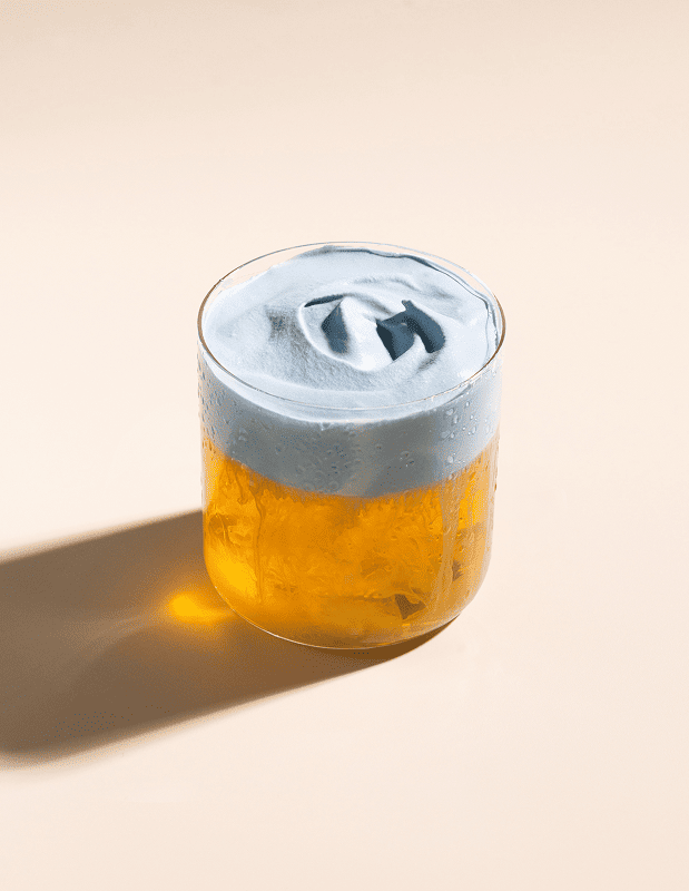 Glass with a layered drink on a beige background