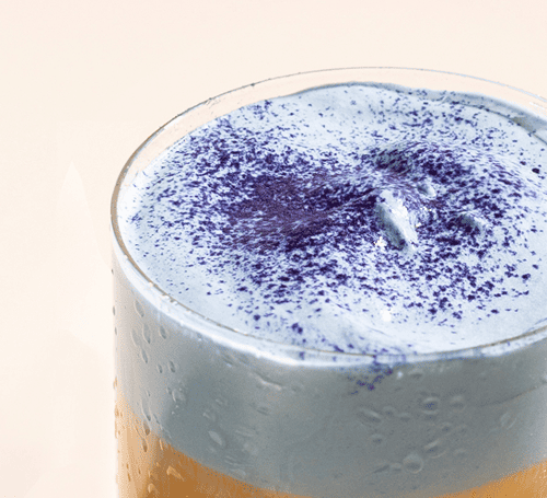Glass with a layered drink on a beige background