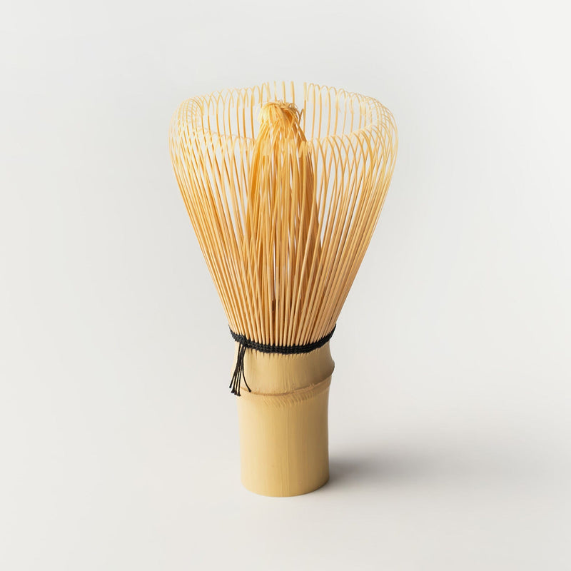 A handcrafted chasen by Rishi Tea & Botanicals, also known as a bamboo tea whisk, stands upright on a plain white background.
