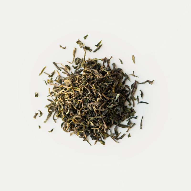 A pile of Darjeeling First Flush Tumsong EX3 green tea from Rishi Tea & Botanicals on a white surface.