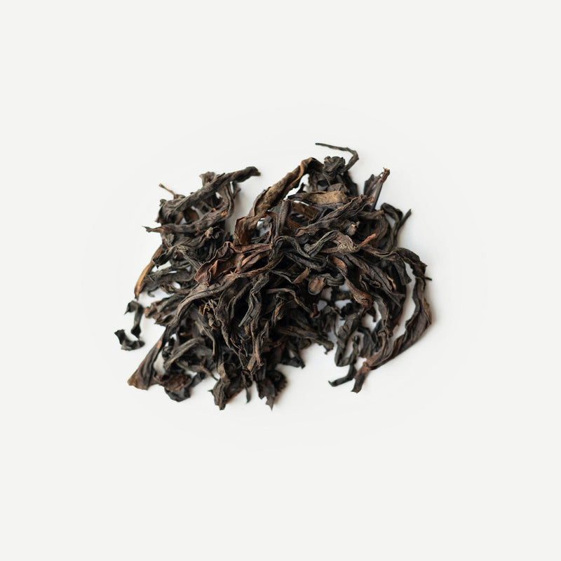 A pile of loose, dried Wuyi rock tea leaves from Rishi Tea & Botanicals rests on a plain white background.