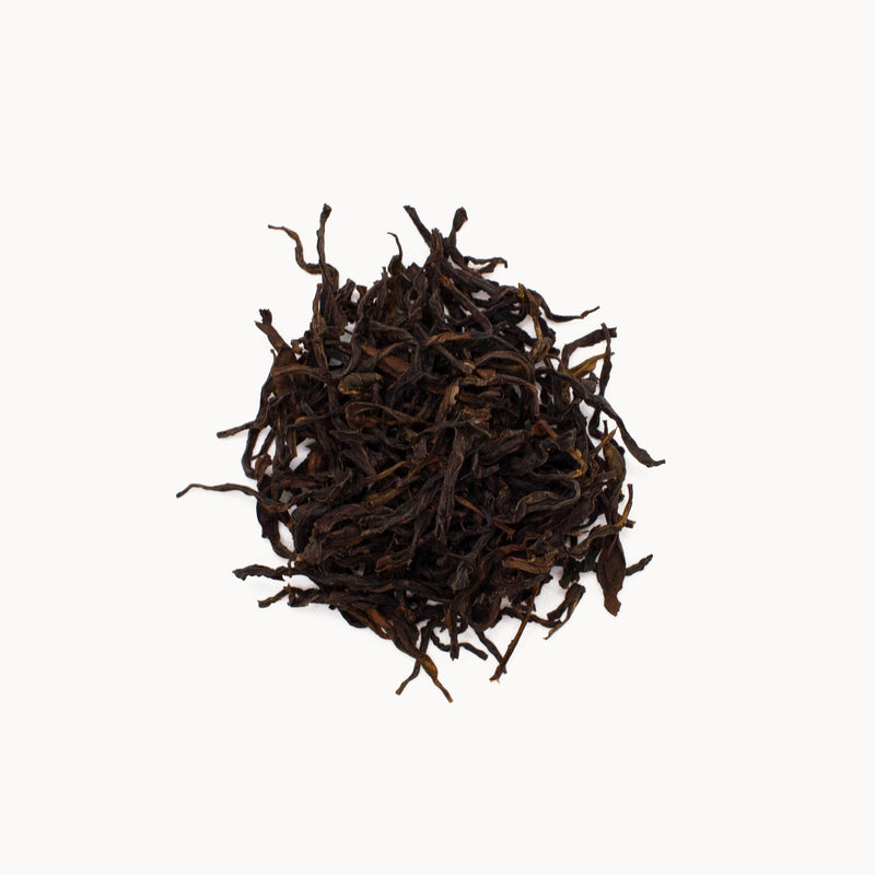 A small pile of Phoenix Dancong Song Zhong loose-leaf tea by Rishi Tea & Botanicals, featuring complex notes, against a white background.
