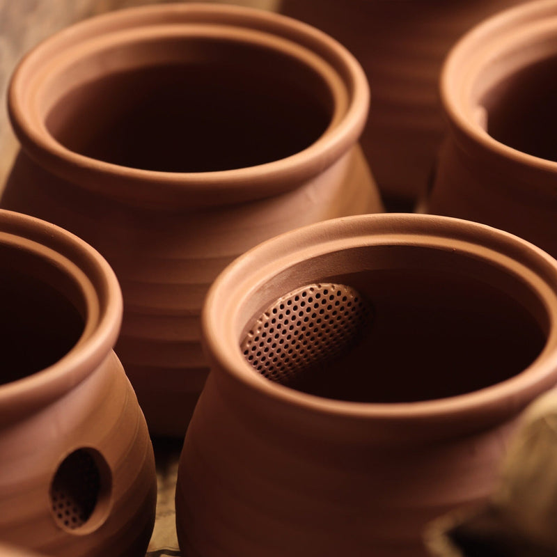 Close-up of several unglazed clay pots, including one with side perforations—a signature of Chato Co., Ltd.'s Tokoname kyusu teapots, crafted from shudei clay and often featuring a ceramesh filter.