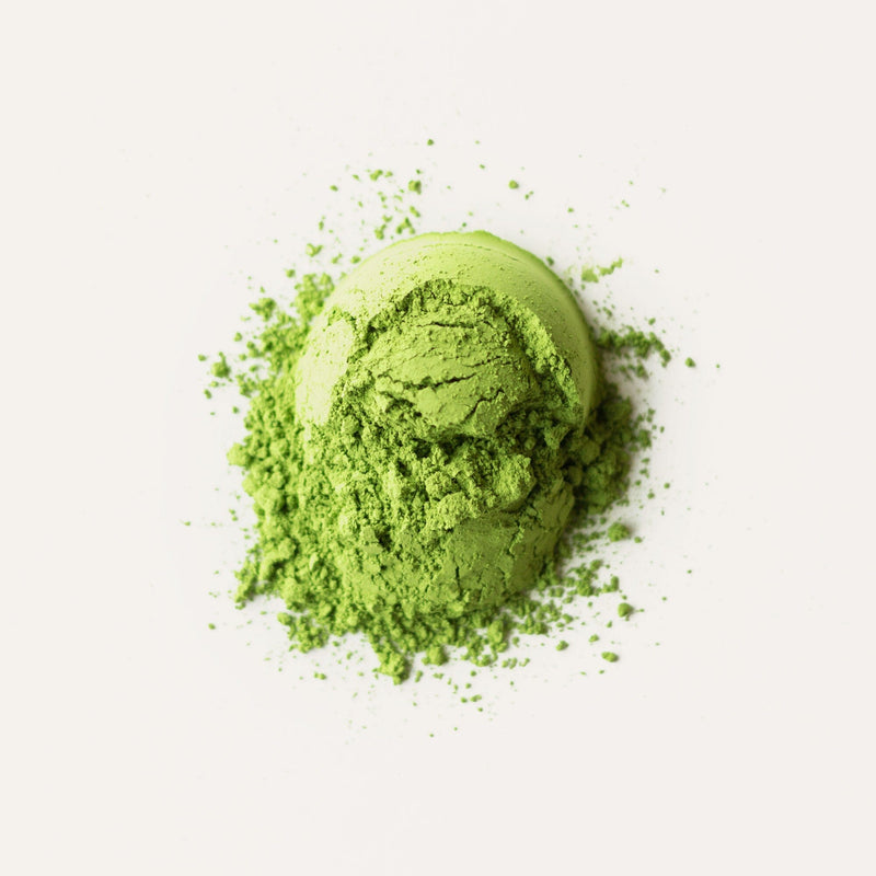 A scoop of Matcha Asahi from Rishi Tea & Botanicals lies partially spread on a white surface.
