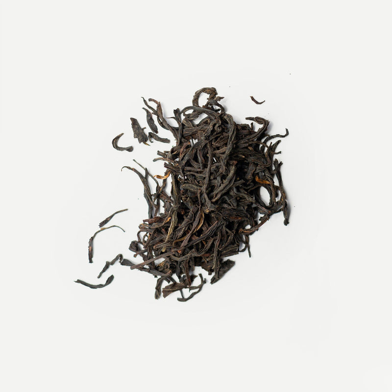 A pile of loose Yunnan Lily Black tea leaves from Rishi Tea & Botanicals is arranged against a white background.