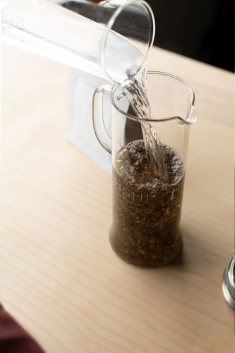 Adding water over loose-leaf tea during cold brew tea making process