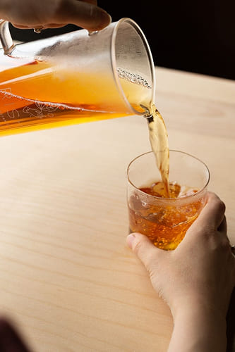 Pouring cold brew tea into a glass to serve